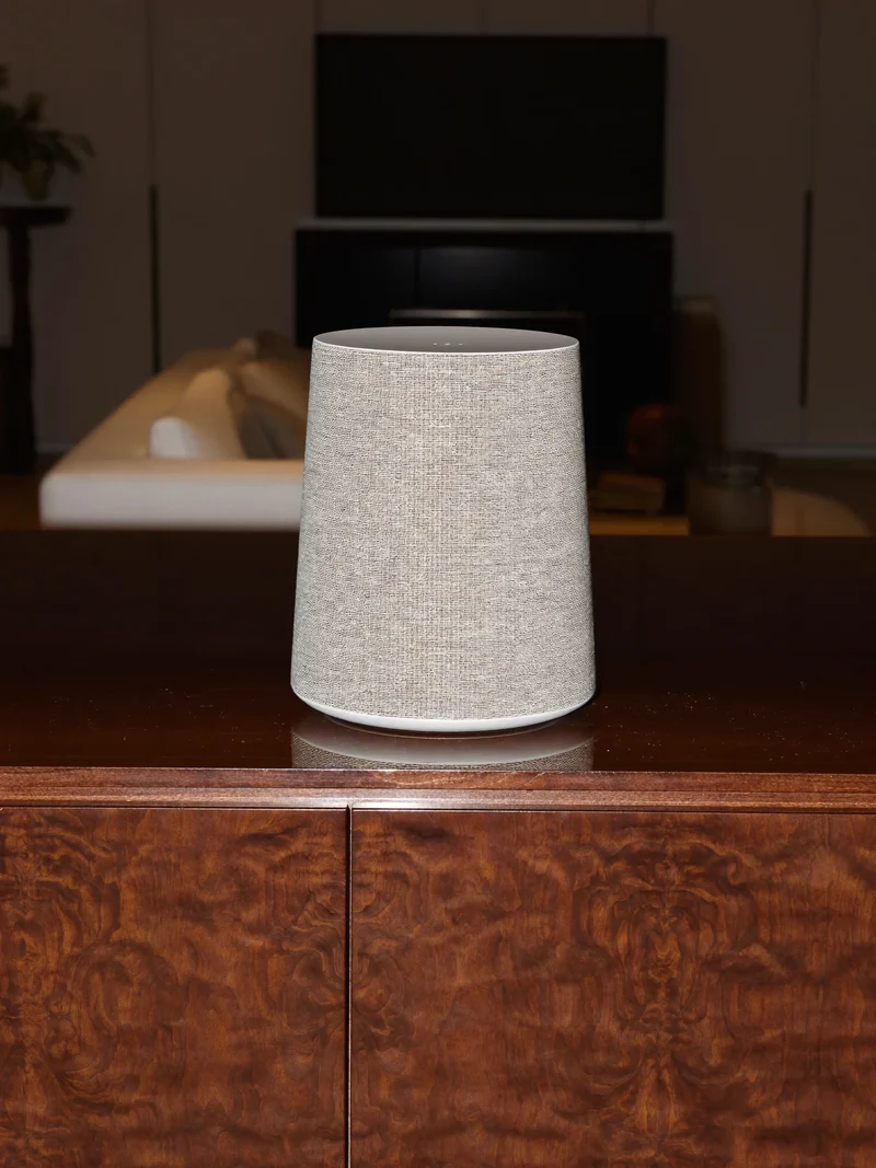Enceinte en tissu maillé sur un buffet en noyer, salon éclairé en soirée